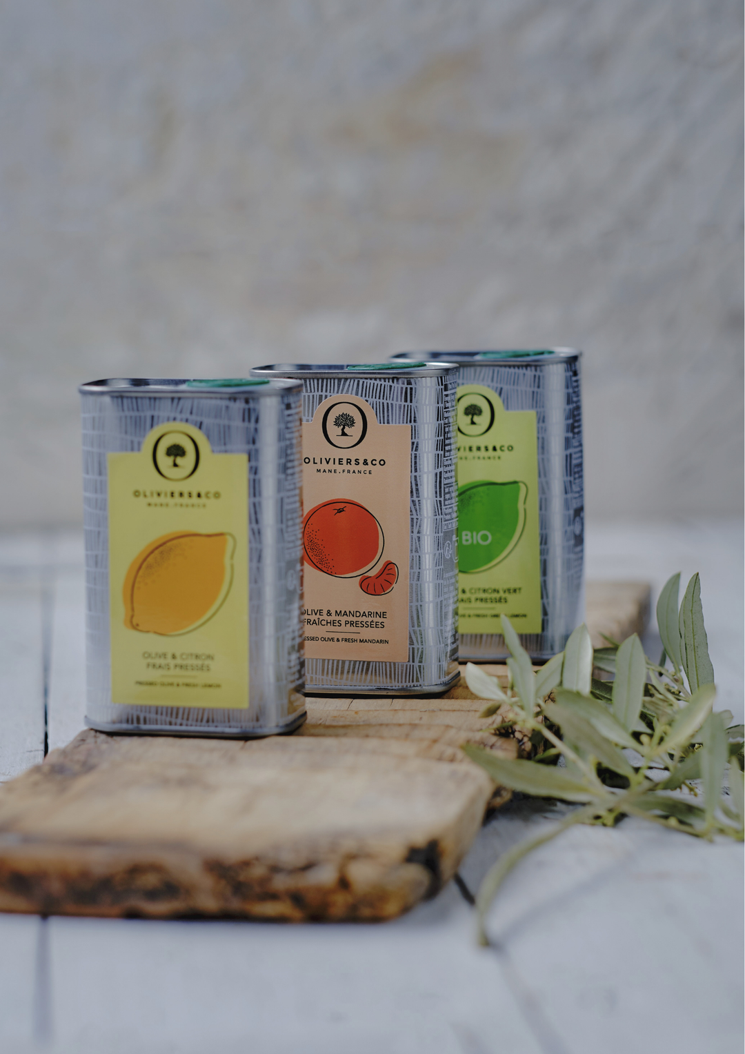 Trois bouteilles d’huile d’olive extra vierge Oliviers & Co aromatisées au citron, au citron vert bio et à la mandarine, présentées ensemble.