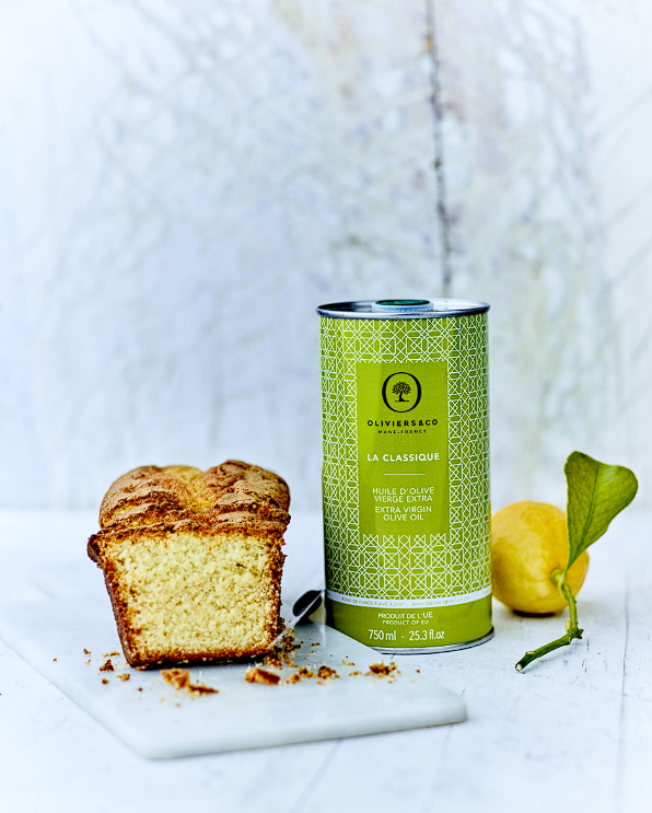 750 ml láhev extra panenského olivového oleje La Classique, původem ze Španělska, umístěná na neutrálním šedém pozadí s citronem, brioškou a krájecí deskou.
